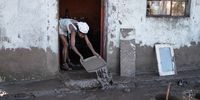 A resident of an informal settlement scrapes mud out of her dwelling after a flood near Mthatha on 12 June 2025. (Photo by Emmanuel Croset / AFP)
