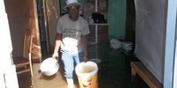 Erick Nyathi tries to empty the water out of his shack. (Photo: Vincent Lali)