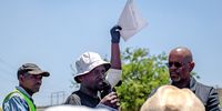 Jeffrey Mphohoni (centre), a Phumla Mqashi resident and organiser of the protest, speaks to the crowd outside the Lenasia South Civic Centre on 2 December 2024. Bonginkosi Xaba (right), a Johannesburg Water representative, stands ready receive the protesters’ memorandum of demands. (Photo: Julia Evans)