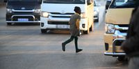 A school child crosses a road of taxi buses in the Katleong township of South Africa, on Wednesday, May. 15, 2024. Photographer: Leon Sadiki/Bloomberg via Getty Images